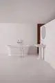 Weiße Badewanne und Waschbecken unter klaren Linien in einem minimalistischen Raum. Ideal Standard Badearmatur ist an der Wand mit zwei Hebelgriffen aus Chrom installiert.